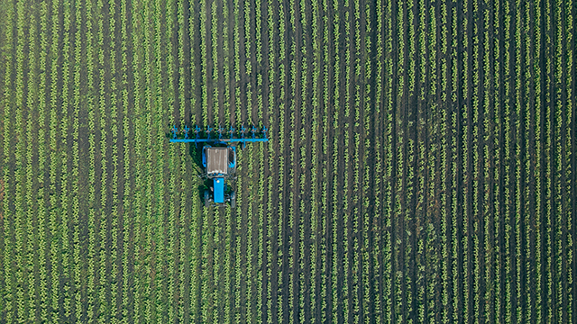 Farm machinery in a crop field from above.