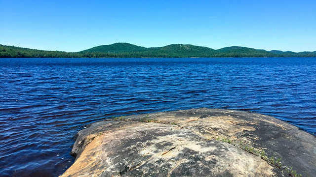 Under a cloudless blue sky, Lake Lila gleams in the William C. Whitney Wilderness Area in Adirondack Park.