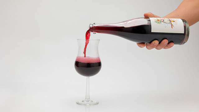 Pouring a glass of red beverage.